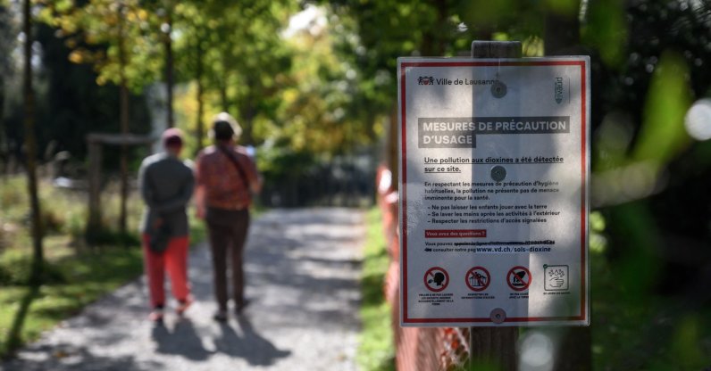 A warning board next to the dioxin-polluted playground of la Sallaz surrounded by orange fences in Lausanne, Switzerland, Oct. 15, 2021. (AFP Photo)
