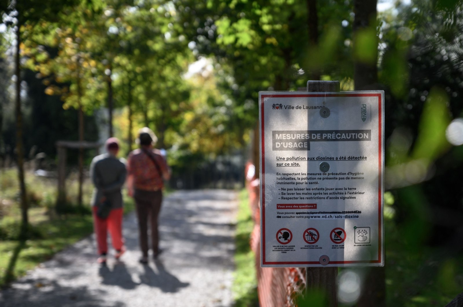 A warning board next to the dioxin-polluted playground of la Sallaz surrounded by orange fences in Lausanne, Switzerland, Oct. 15, 2021. (AFP Photo)