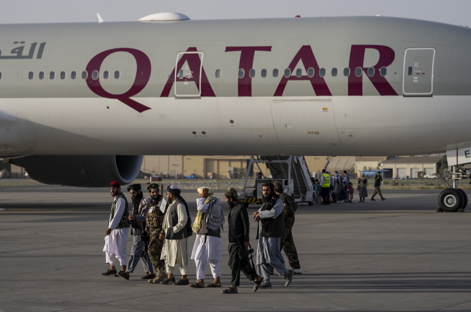 Taliban fighters walk past a Qatar Airways aircraft at the airport in Kabul, Afghanistan, Sept. 9, 2021. (AP Photo)