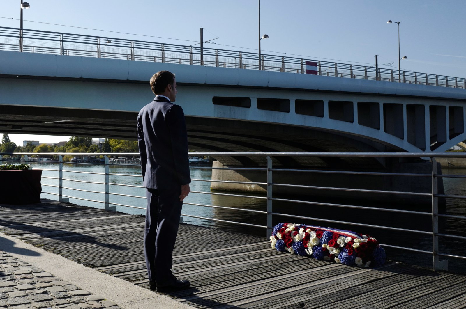 French President Emmanuel Macron stands at attention after laying a wreath near the Pont de Bezons during a ceremony commemorating the 60th anniversary of the massacre of Oct. 17, 1961, a murderous repression by the French police of a demonstration by Algerians in Paris during the violent decolonization process, in Colombes near Paris, France, Oct. 16, 2021. (Reuters Photo)