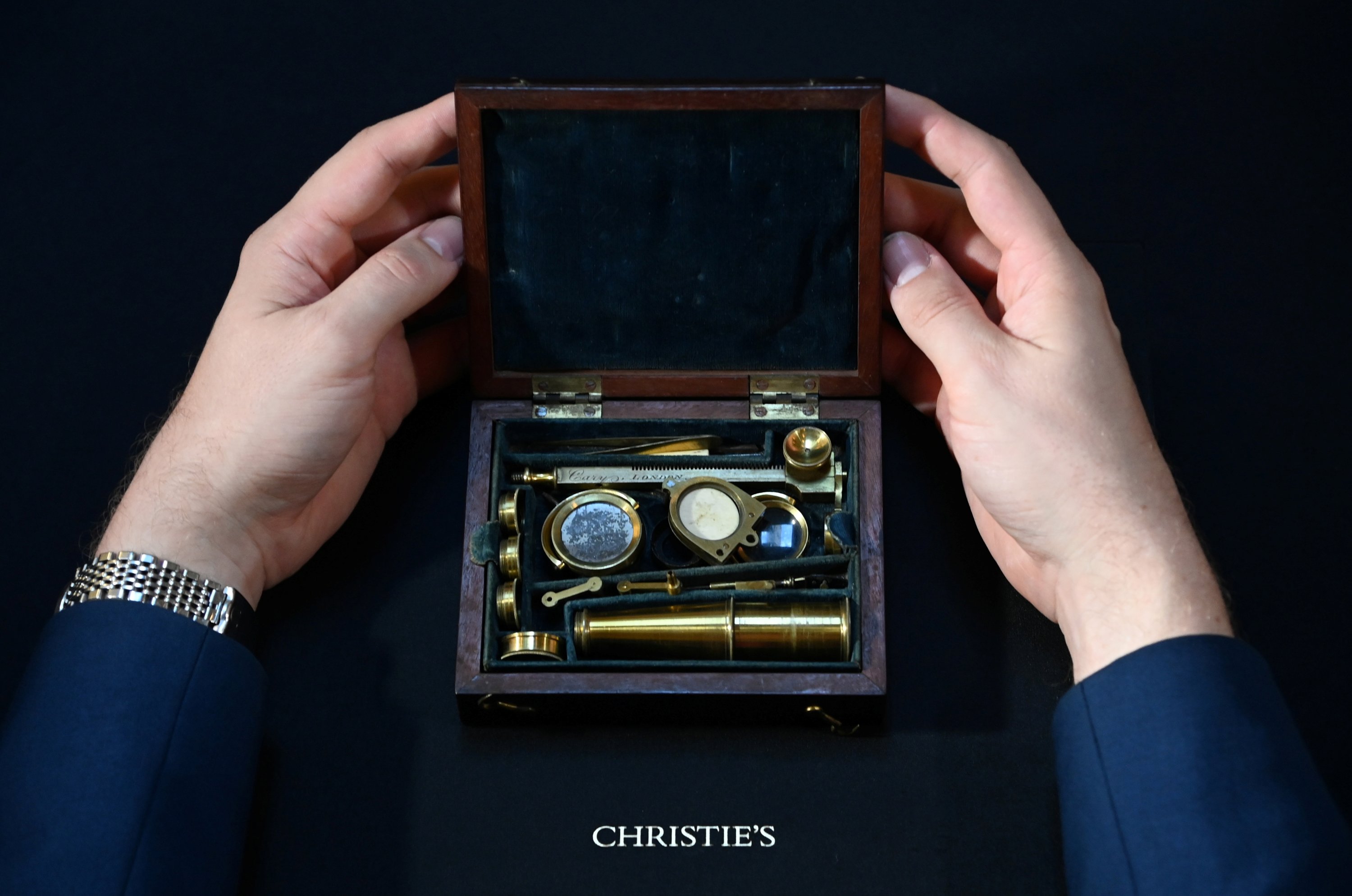 James Hyslop, head of Scientific Instruments, Globes and Natural History at Christie's, demonstrates the Darwin Family Microscope, owned and used by the English naturalist and founder of the concept of evolution, Charles Darwin, which will be offered at auction as part of Christie's Classic Week, London, Britain, Oct. 14, 2021. (Reuters Photo)