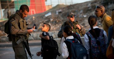 Israeli border police check Palestinians' identification cards at a checkpoint as they exit the Arab neighborhood of Issawiyeh in East Jerusalem, occupied Palestine, Oct. 22, 2015. (AP Photo)