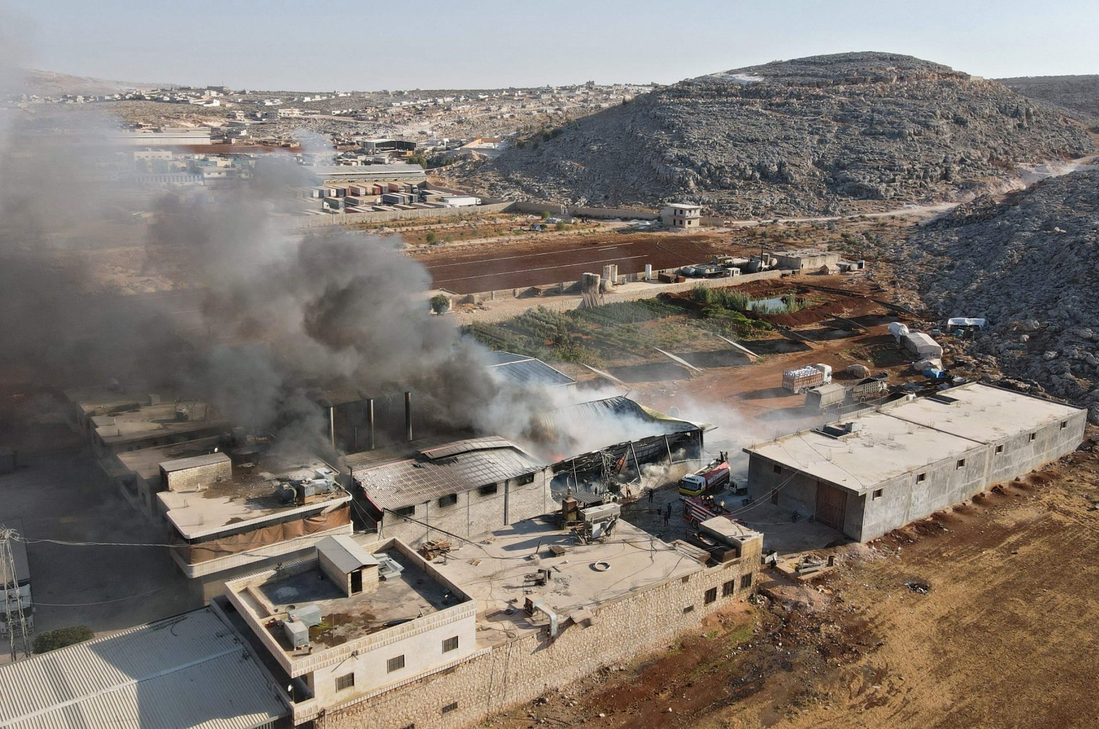 An aerial view shows smoke billowing from a warehouse after reported shelling on the town of Sarmada in Idlib province, northwestern Syria, Oct. 16, 2021. (AFP Photo)