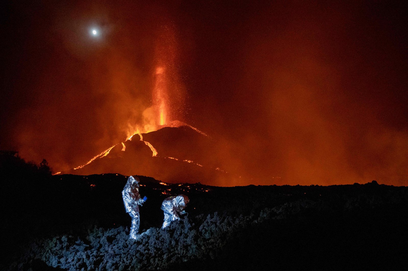 Members of the Spanish Military Emergency Unit (UME) monitor the evolution of a new lava flow from the erupted Cumbre Vieja volcano, on the Canary island of La Palma, Spain, Oct. 16, 2021. (UME via AFP)