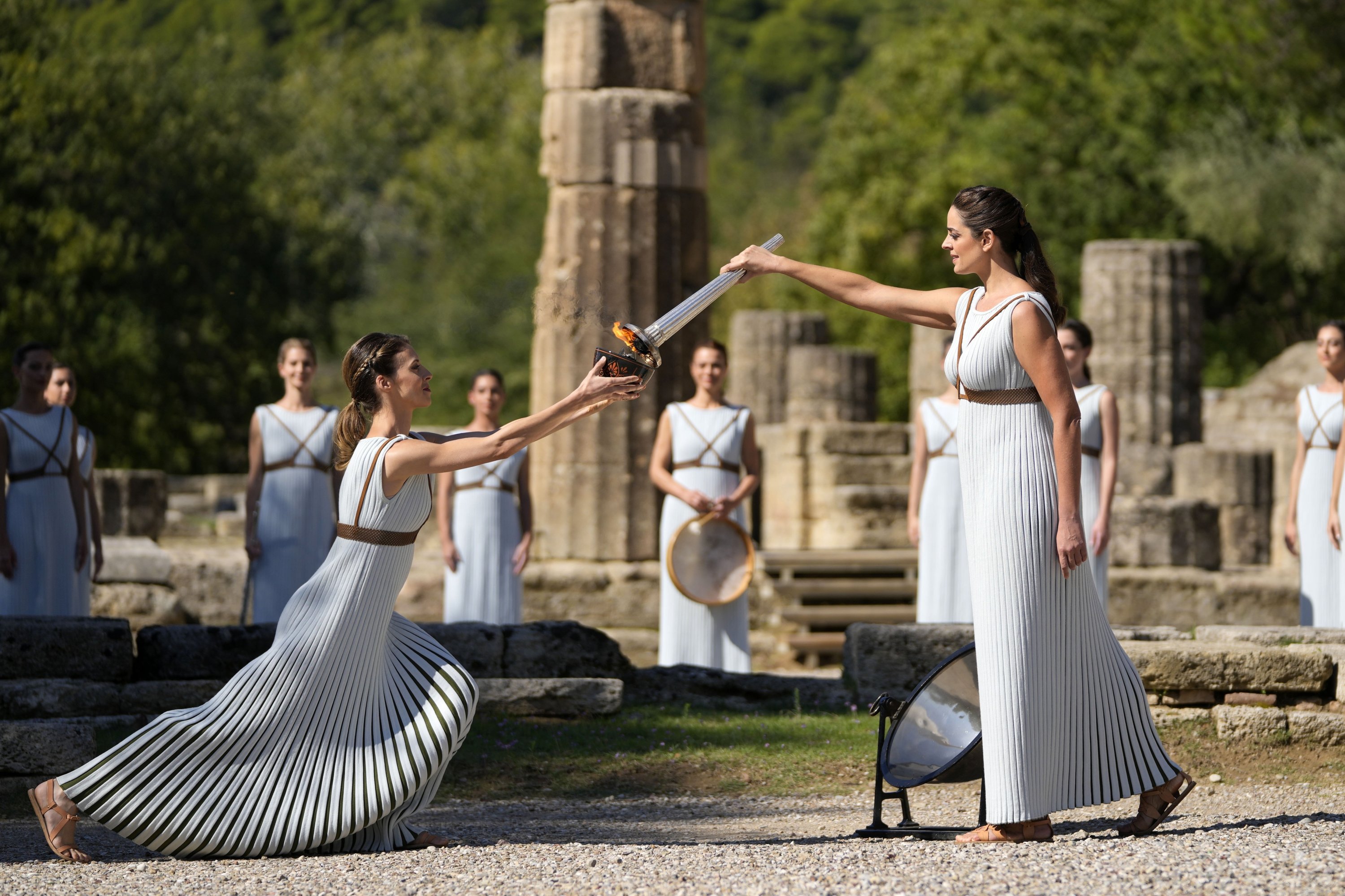 Greek actress Xanthi Georgiou (R) playing the role of the high priestess, holds the torch during the lighting of the Olympic flame at Ancient Olympia site, birthplace of the ancient Olympics in southwestern Greece, Oct. 18, 2021. (AP Photo)