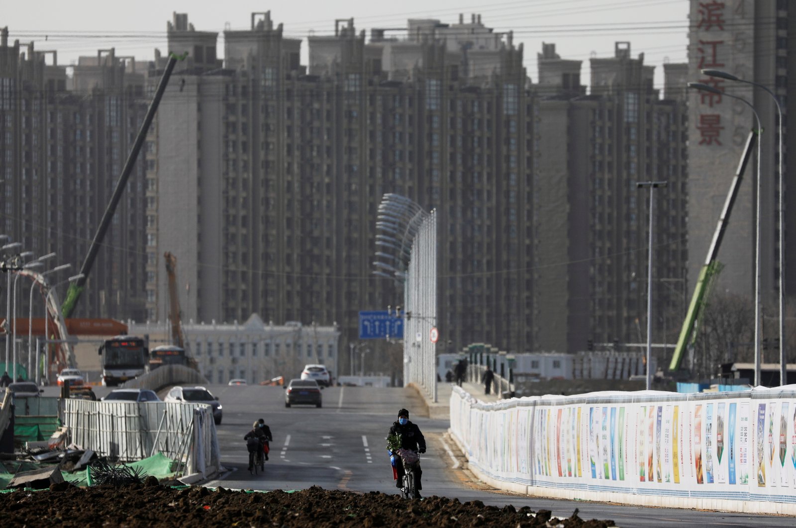 A man rides a bicycle next to a construction site near residential buildings in Beijing, China, Jan. 13, 2021. (Reuters Photo)