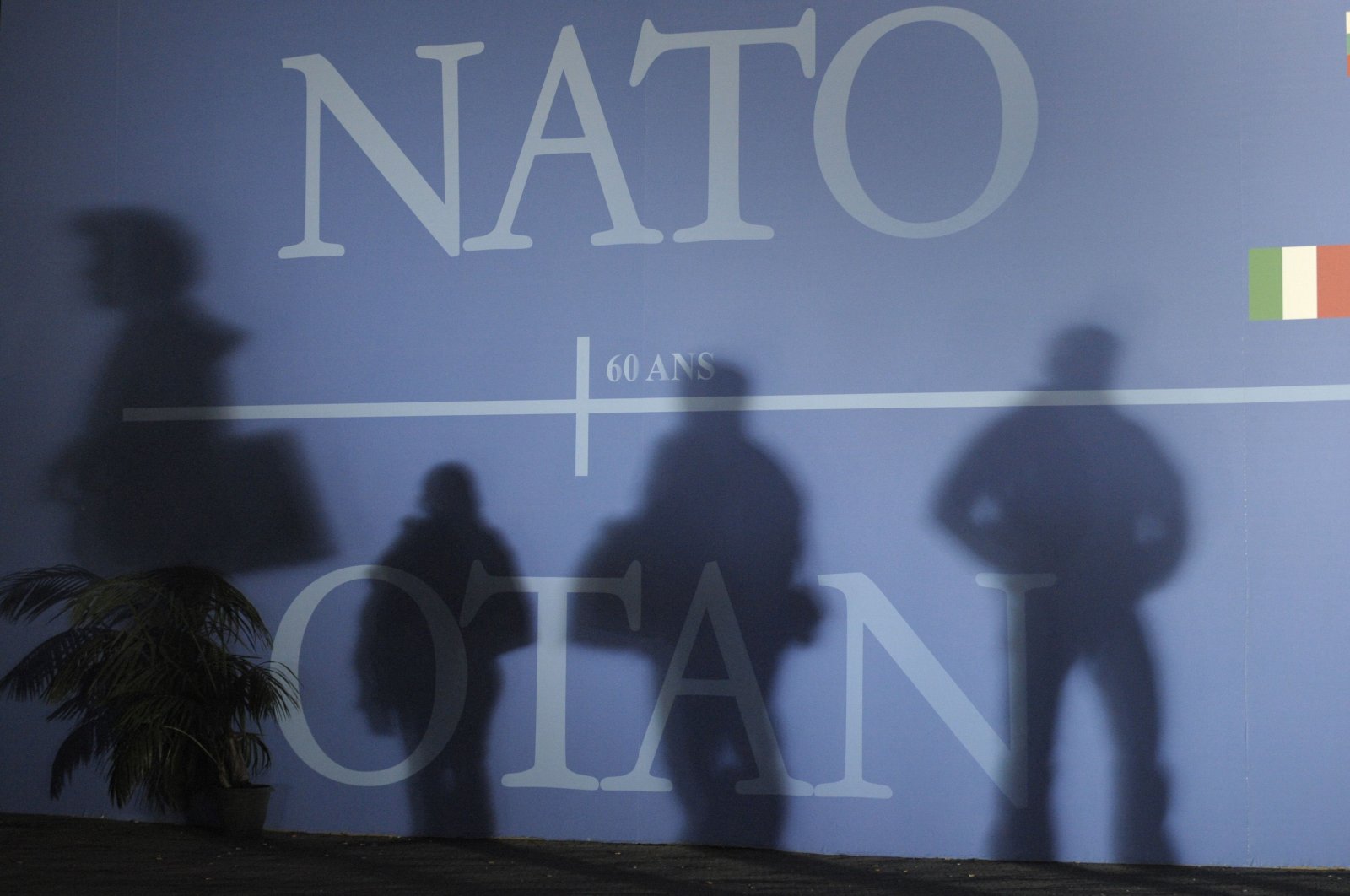 Attendees' shadows are cast on a wall decorated with the NATO logo and flags of NATO countries in Strasbourg, eastern France, April 2, 2009. (AFP File Photo)