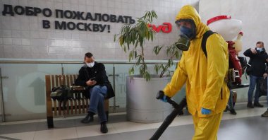 An employee of the Federal State Center for Special Risk Rescue Operations of Russia Emergency Situations disinfects Leningradsky railway station with the sign reading "Welcome to Moscow" on the wall in Moscow, Russia, Oct. 19, 2021. (AP Photo)