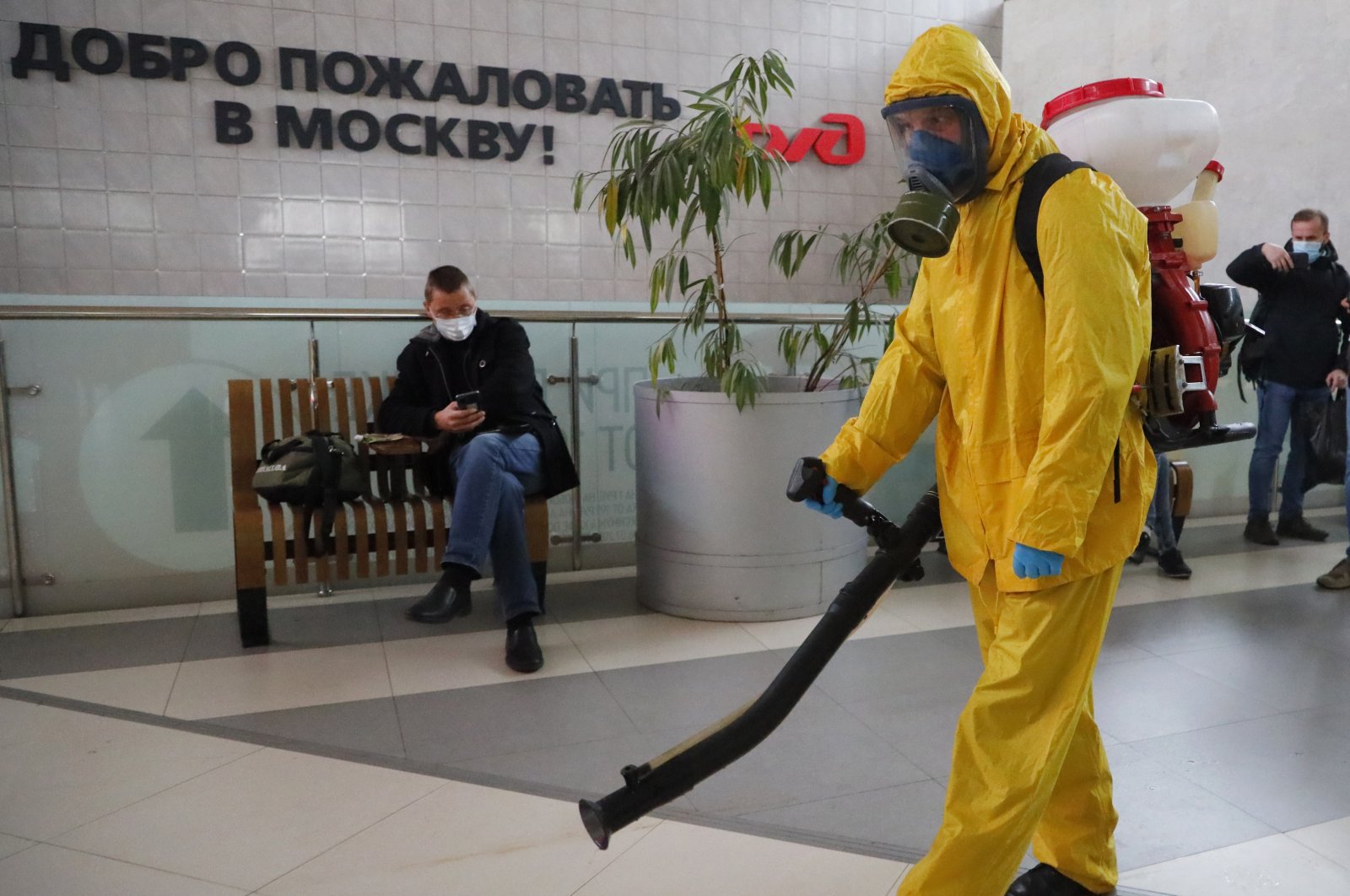 An employee of the Federal State Center for Special Risk Rescue Operations of Russia Emergency Situations disinfects Leningradsky railway station with the sign reading "Welcome to Moscow" on the wall in Moscow, Russia, Oct. 19, 2021. (AP Photo)