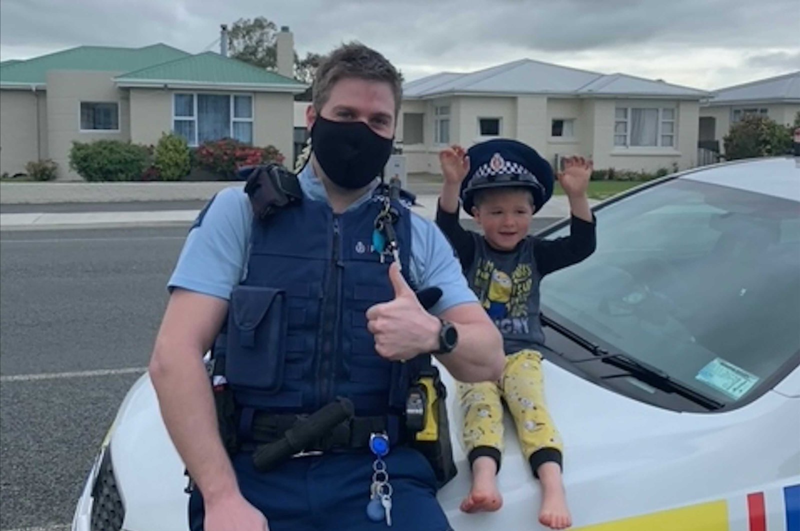 An officer identified only as Constable Kurt sits on his patrol car with a 4-year-old boy who is not identified, in the South Island city of Invercargill, New Zealand, Oct. 15, 2021. (NZ Police via AP)