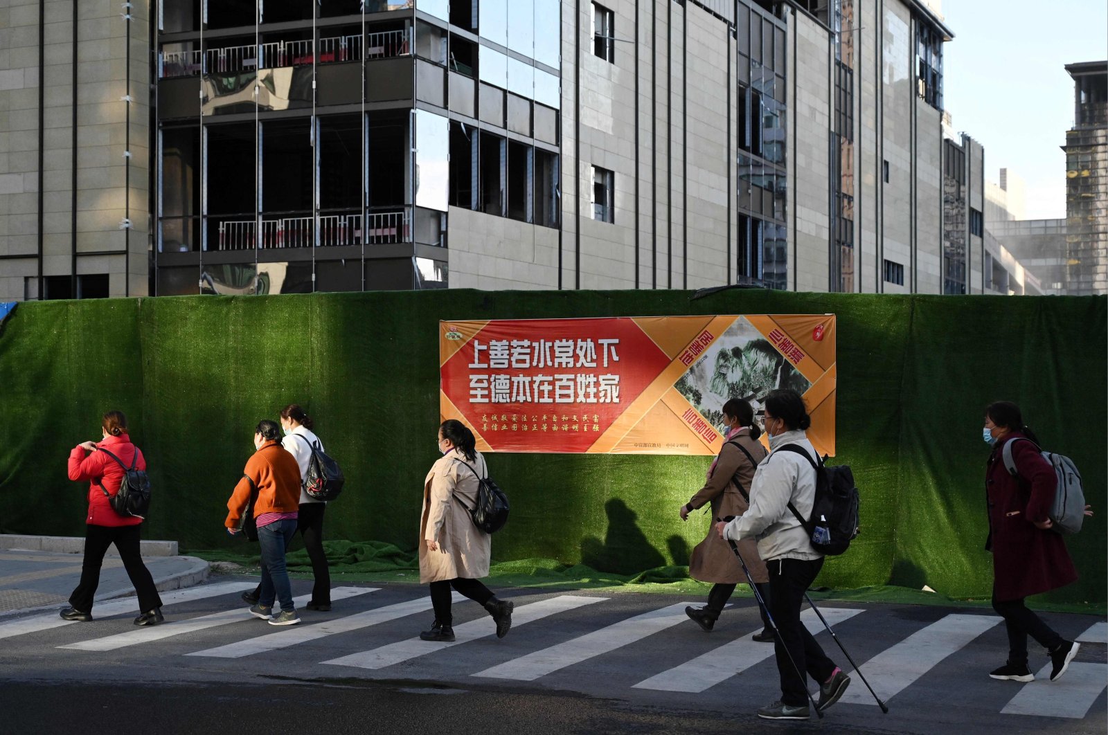 People walk past a construction site in Beijing, China, Oct. 19, 2021.  (AFP Photo)
