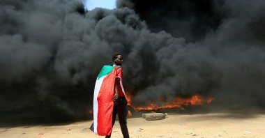 A person wearing a Sudanese flag stands in front of a burning pile of tires during a protest against the prospect of military rule in Khartoum, Sudan, Oct. 21, 2021. (REUTERS Photo)