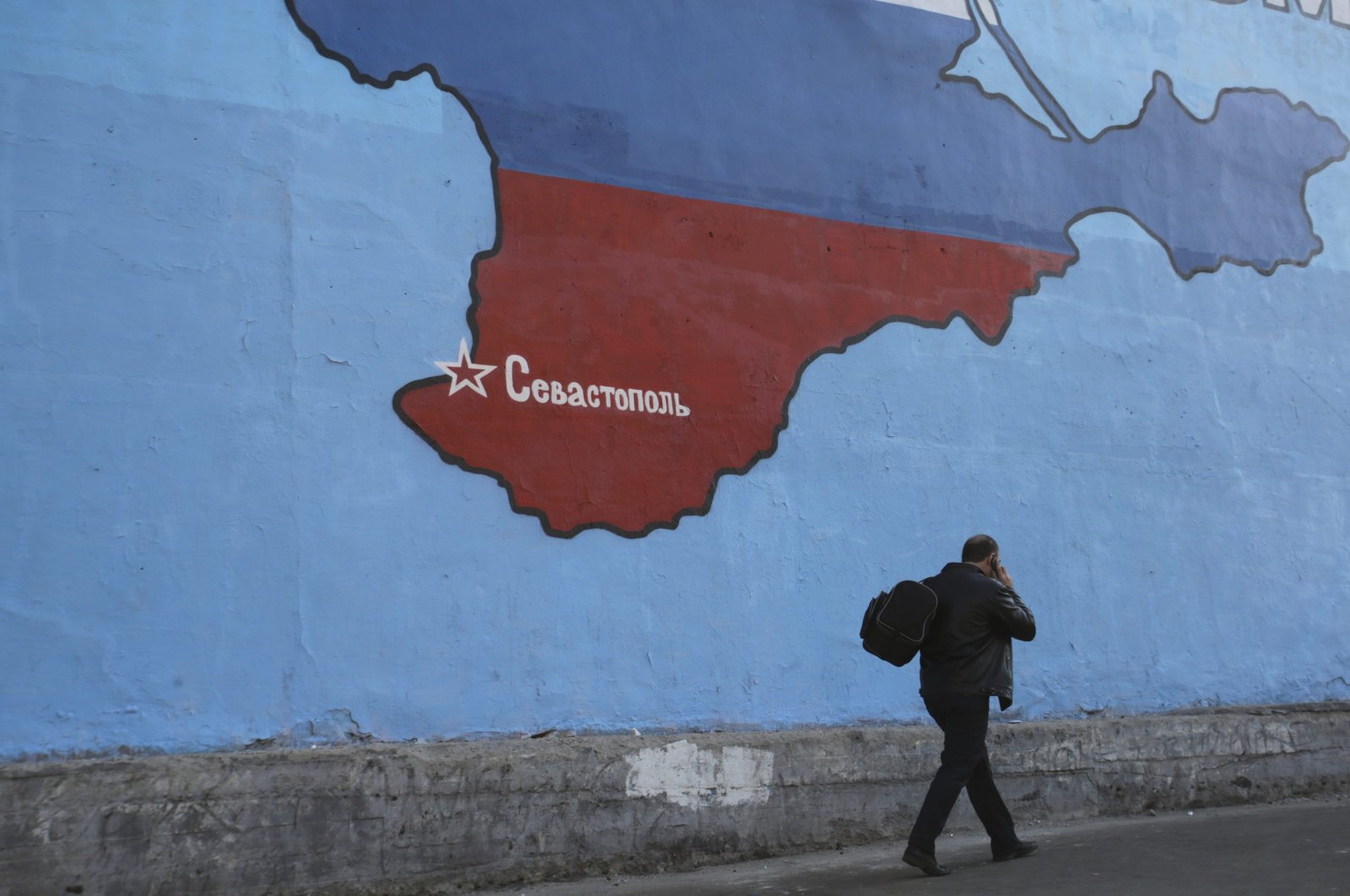 A man passes a mural showing a map of Crimea in the Russian national colours on a street in Moscow, Russia, March 25, 2014. (Reuters Photo)