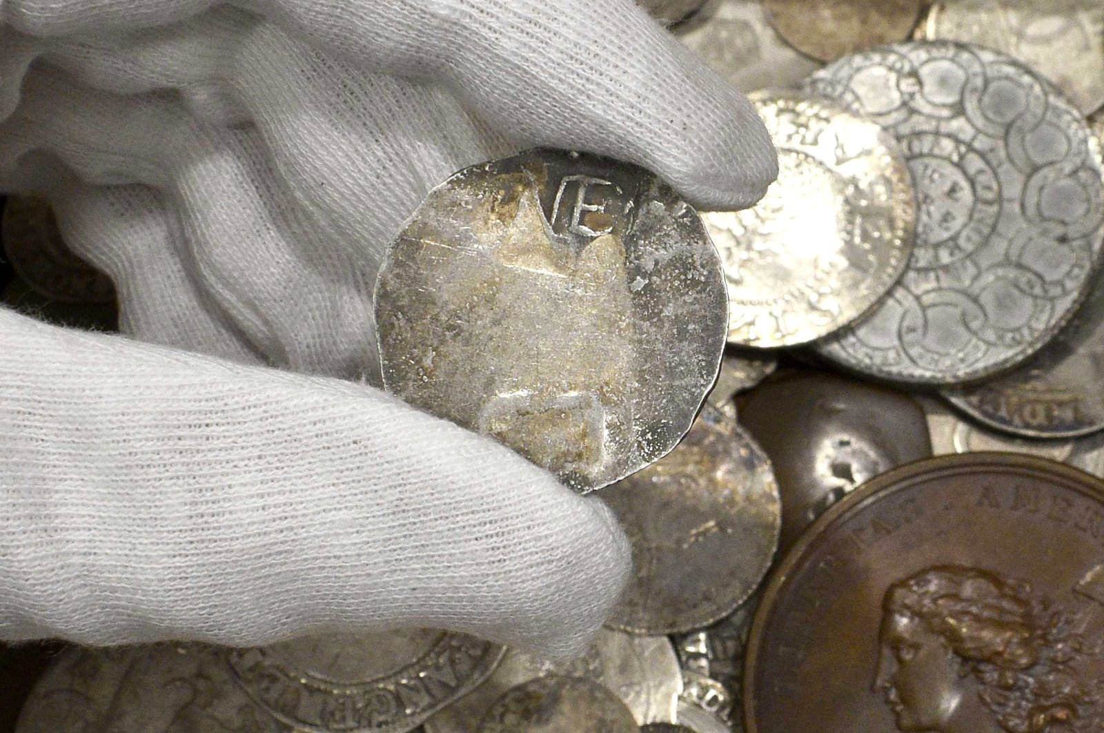 A rare 17th century 1 shilling coin is displayed above a metal box containing other coins, at the auction house, in London. Sept. 9, 2021. (AP Photo)