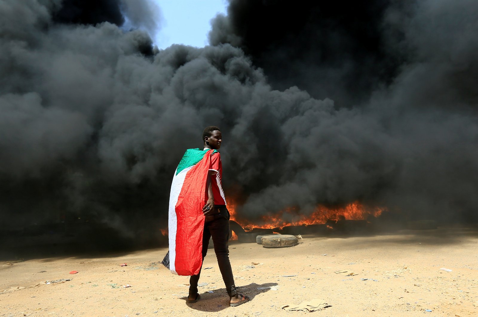 A person wearing a Sudanese flag stands in front of a burning pile of tires during a protest against the prospect of military rule in Khartoum, Sudan, Oct. 21, 2021. (REUTERS Photo)