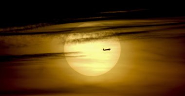 A plane passes by the rising sun in Frankfurt, Germany, Oct. 1, 2021. (AP Photo)