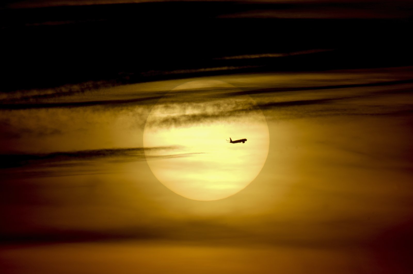 A plane passes by the rising sun in Frankfurt, Germany, Oct. 1, 2021. (AP Photo)