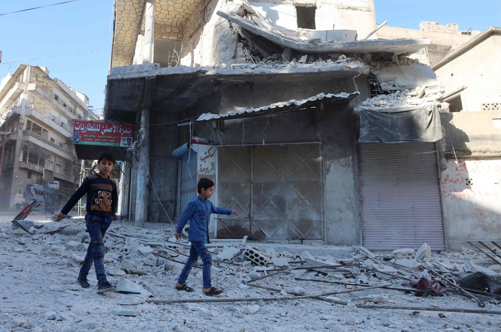 People walk past debris at the site of shelling in the Syrian town of Ariha in the opposition-held northwestern province of Idlib, Syria, Oct. 20, 2021. (AFP Photo)