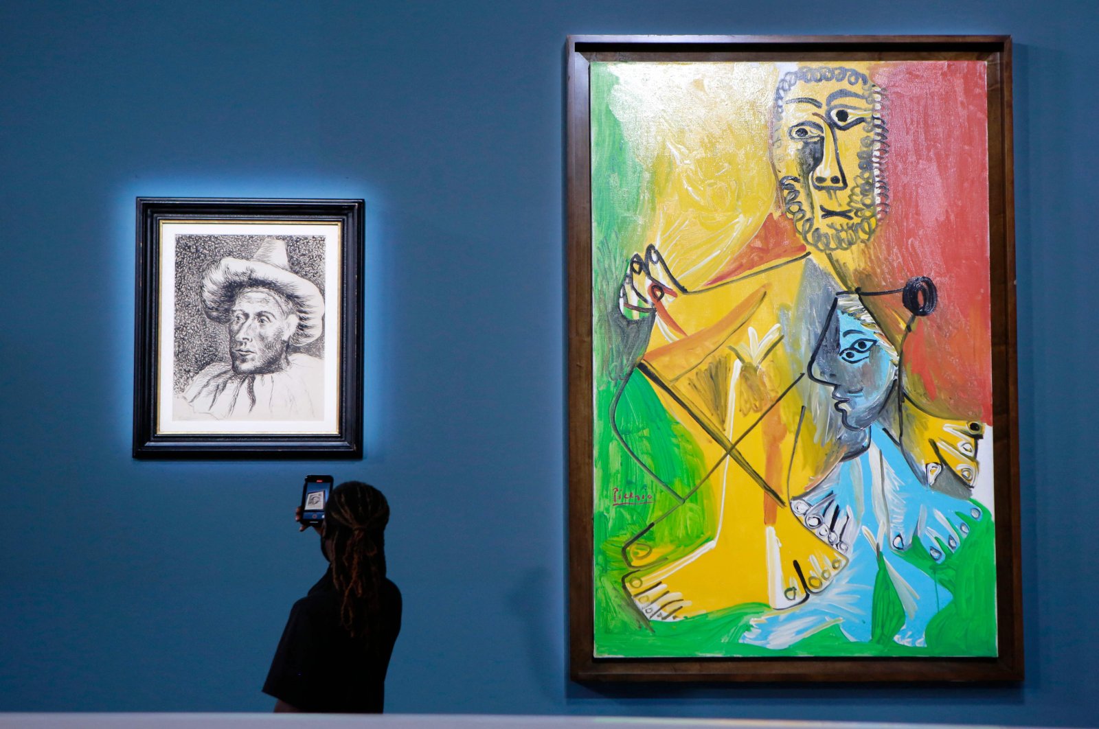 A guest takes a personal photograph of Spanish artist Pablo Picasso's "Pierrot" (L), near "Homme et enfant," before the start of a Sotheby's auction of 11 works by Pablo Picasso, in Las Vegas, U.S., Oct. 23, 2021. (AFP Photo)
