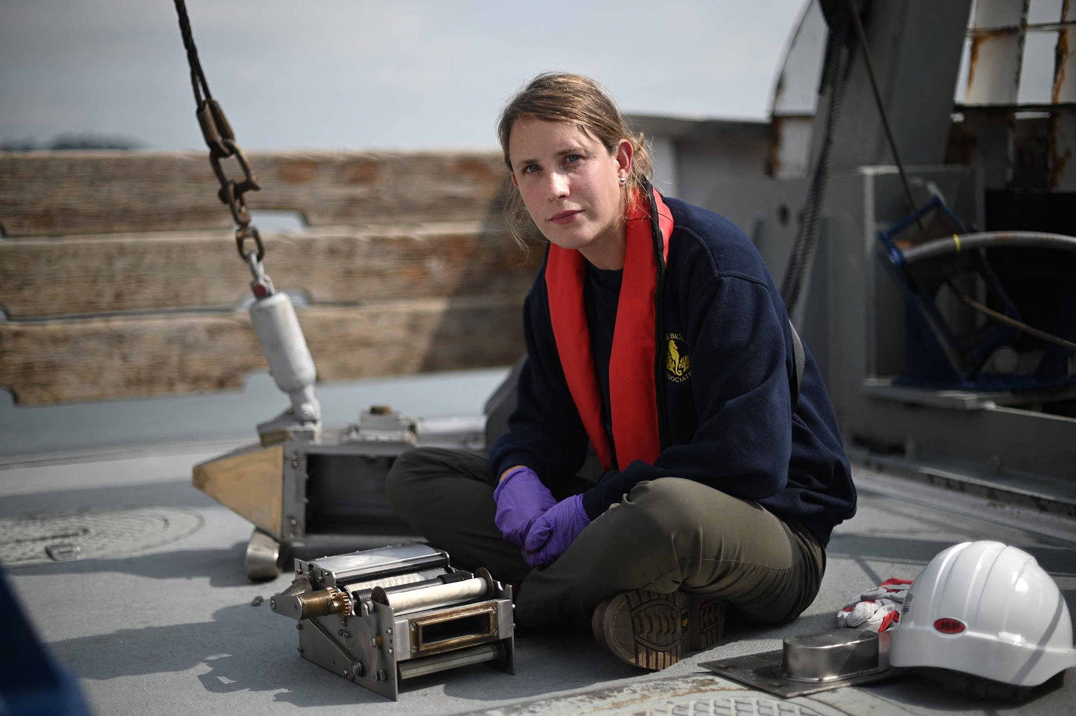Scientist Clare Ostle poses alongside a recording device containing silk scrolls, on the MBA Sepia research vessel, off the coast of Plymouth, south England, Aug. 26, 2021. (AFP Photo)