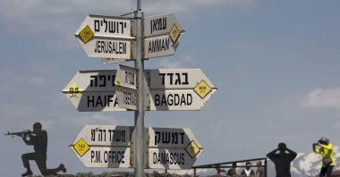 People take photographs next to a mock road sign pointing to Damascus, the capital of Syria, and other cities at an old outpost in the Israeli controlled Golan Heights near the border with Syria, March 22, 2019. (AP Photo)