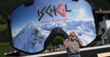 A man removes a protective face mask after photographing himself in front of an advertisement in the shape of ski goggles for the Ischgl ski resort on Sep. 10, 2020 in Ischgl, Austria. (Getty Images)