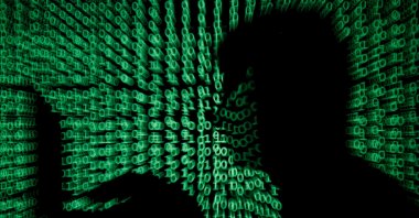 A man holds a laptop computer as cyber code is projected on him in this illustration picture taken on May 13, 2017. (REUTERS)