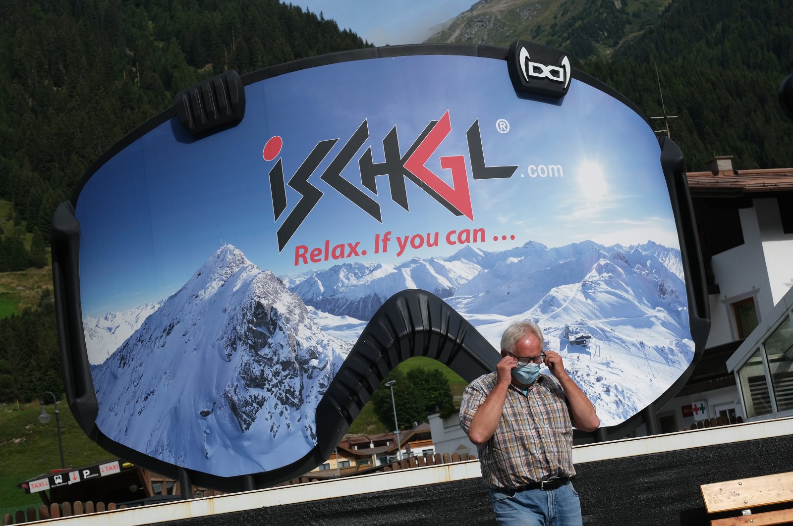 A man removes a protective face mask after photographing himself in front of an advertisement in the shape of ski goggles for the Ischgl ski resort on Sep. 10, 2020 in Ischgl, Austria. (Getty Images)