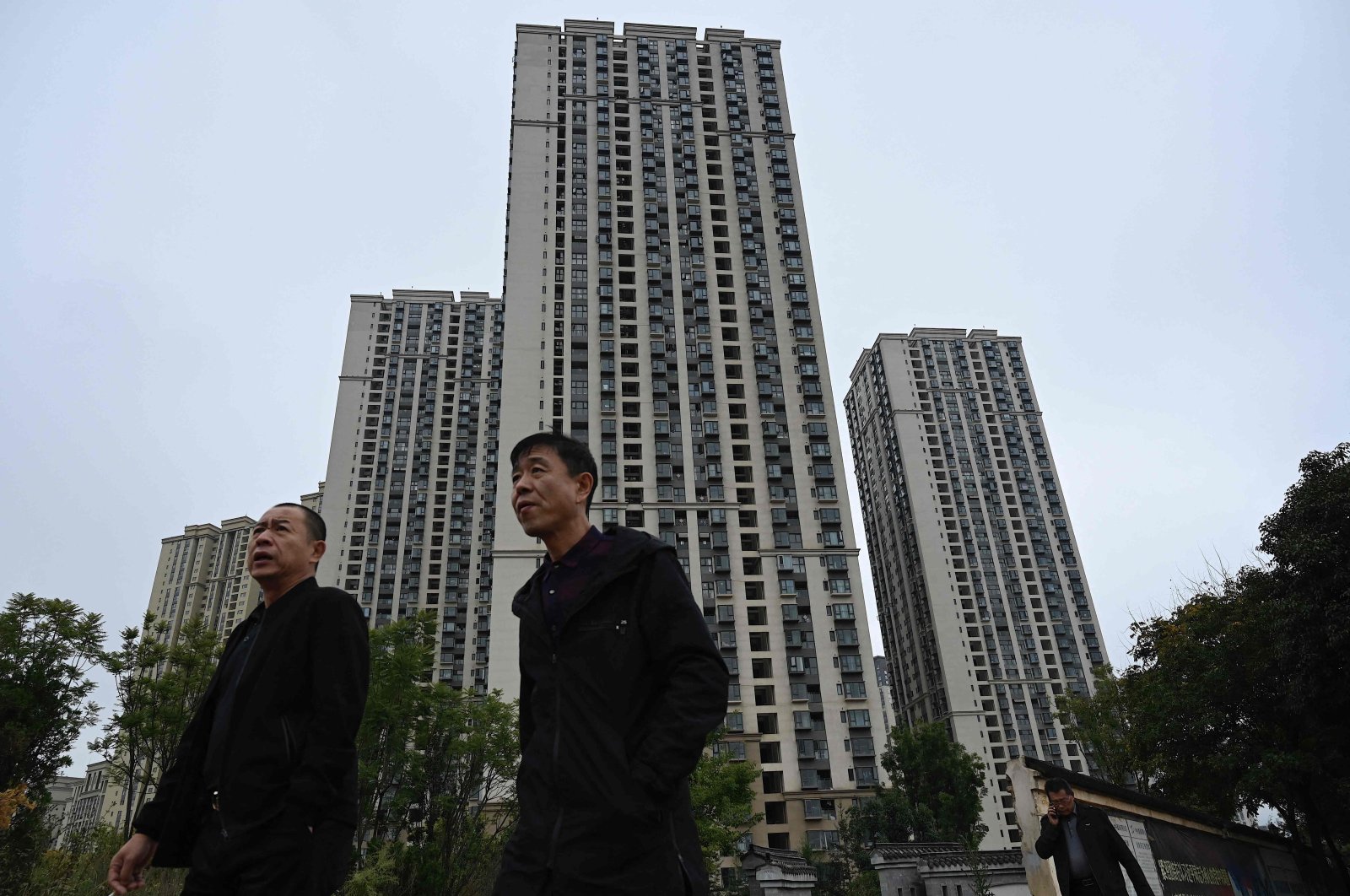 People walk past a housing complex of Chinese property developer Evergrande in Kunming, in southwestern Yunnan province, China, Oct. 23, 2021. (AFP Photo)