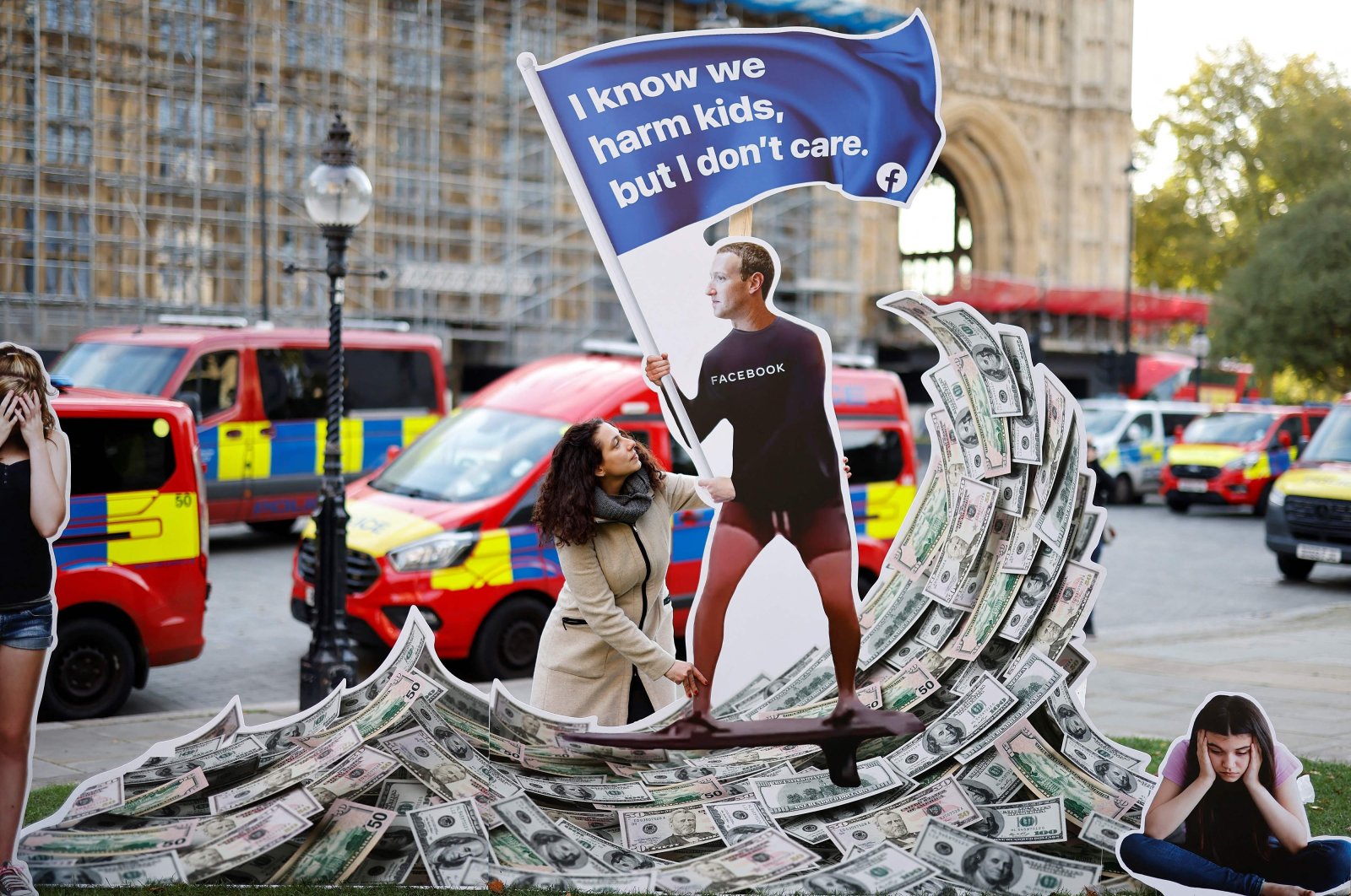 A demonstrator poses with an installation depicting Facebook founder Mark Zuckerberg surfing on a wave of cash and surrounded by distressed teenagers, during a protest opposite the Houses of Parliament in central London, U.K., Oct. 25, 2021. (AFP Photo)
