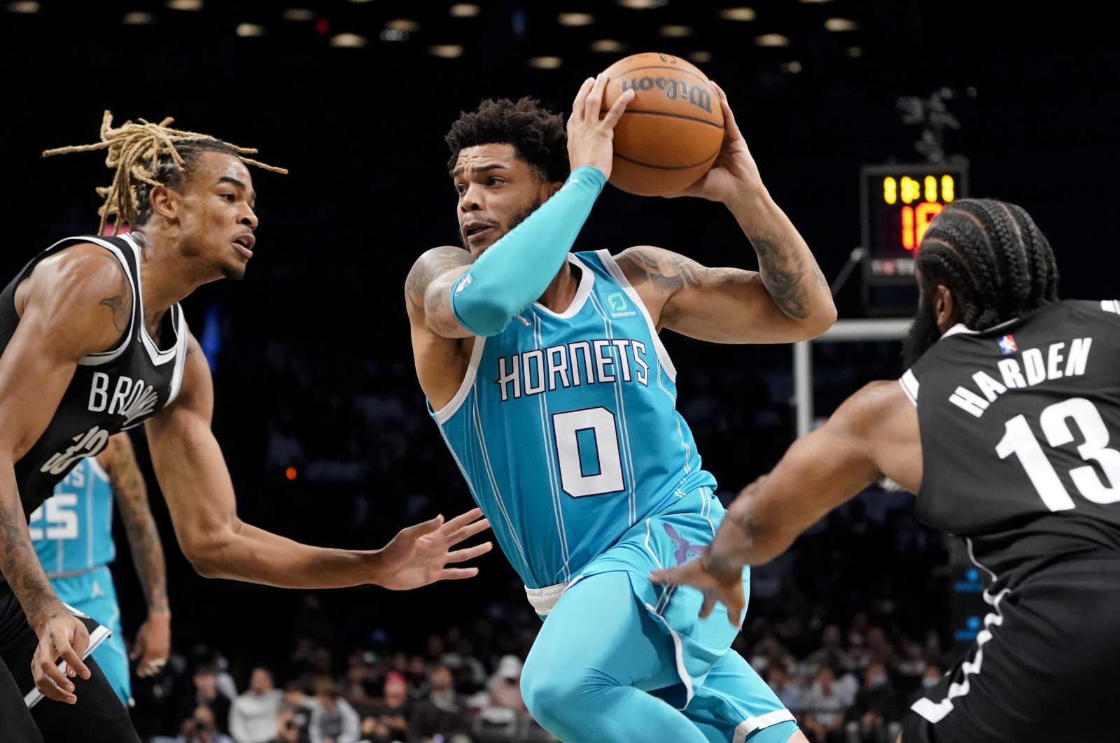 Charlotte Hornets forward Miles Bridges (C) drives past Brooklyn Nets guard James Harden (R) and forward Nic Claxton (L) during the first half of an NBA basketball game, New York, U.S., Oct. 24, 2021. (AP Photo)