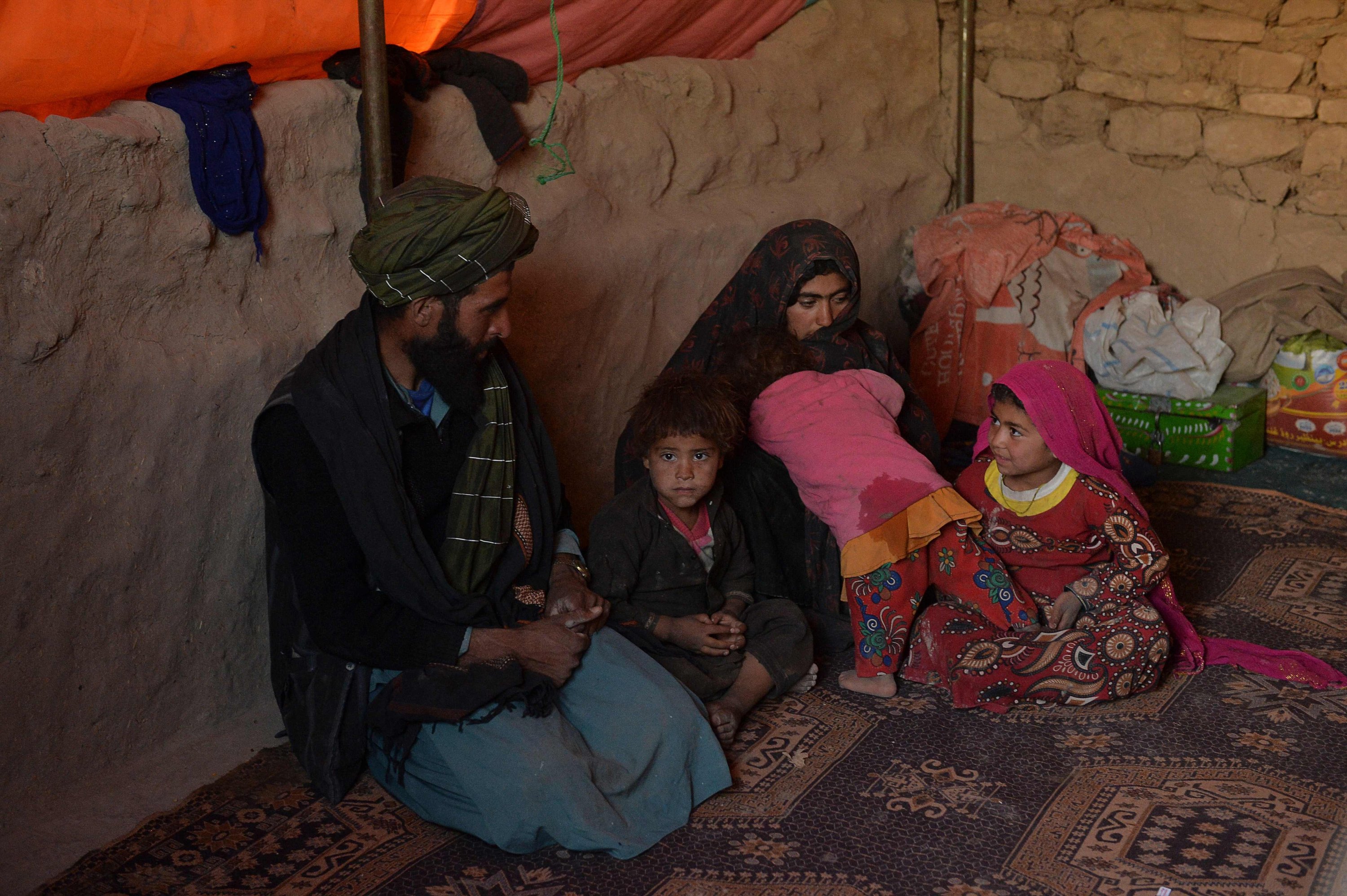 Children Farishteh (R) and Shokriya (2R), who were recently sold to the families of their future husbands, sitting with their parents inside a tent at the Shamal Darya Internally Displaced People (IDP) camp in Qala-i-Naw, Badghis Province, Afghanistan, Oct. 14, 2021. (AFP Photo)