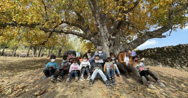 Cuma Karaaslan (C) reads books with children under a tree in the village of Çavuşlar, in Bingöl, eastern Turkey, Oct. 26, 2021. (AA PHOTO)
