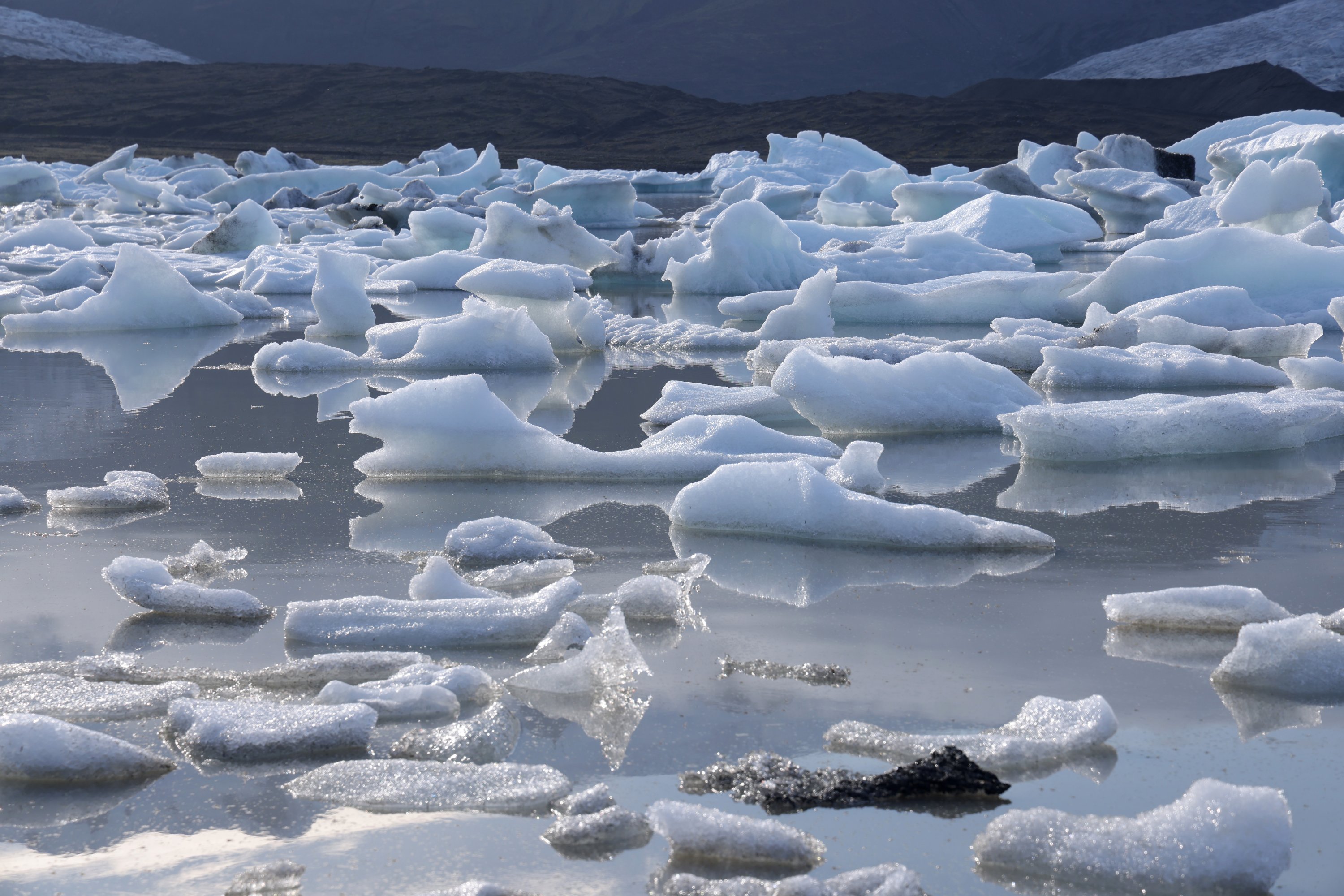 Potongan es jatuh dari gletser Fjallsjokull dalam proses yang disebut calving float di danau Fjallsarlon, dekat Hof, Islandia, 14 Agustus 2021. (Foto oleh Getty Images)