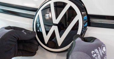 A worker adjusts a VW logo at the assembly line for the Volkswagen (VW) ID 3 electric car of German carmaker Volkswagen, at the Glaeserne Manufaktur production site in Dresden, eastern Germany, June 8, 2021. (AFP Photo)
