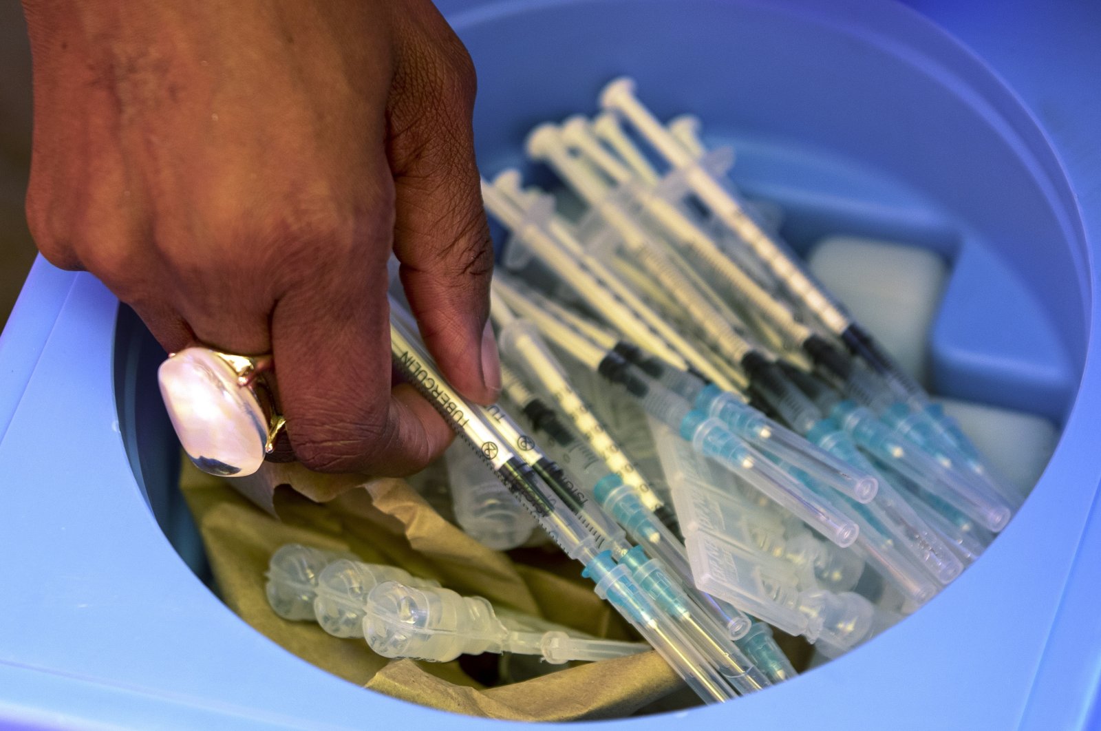 A health worker picks syringes as seniors get vaccinated with the first dose of the Pfizer coronavirus vaccine at the newly opened mass vaccination program for the elderly at a drive-through vaccination center in Johannesburg, South Africa, May 25, 2021. (AP Photo)