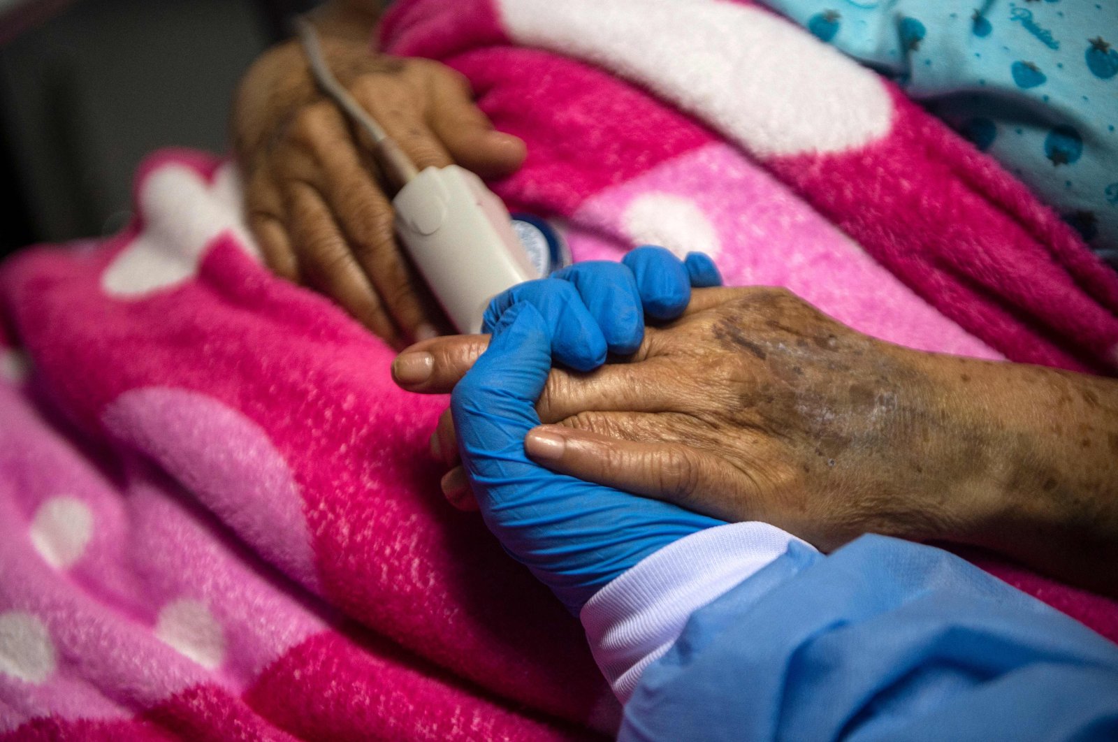 A health professional holds the hand of a COVID-19 patient at the Intensive Care Unit of the Virgen de Fatima contingency hospital in Sullana, Piura, northern Peru, Oct. 19, 2021, (AFP Photo)