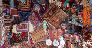 A tourist poses on hand-woven carpets in a historical inn converted into a carpet shop in Göreme, Nevşehir, central Turkey. (Getty Images) 
