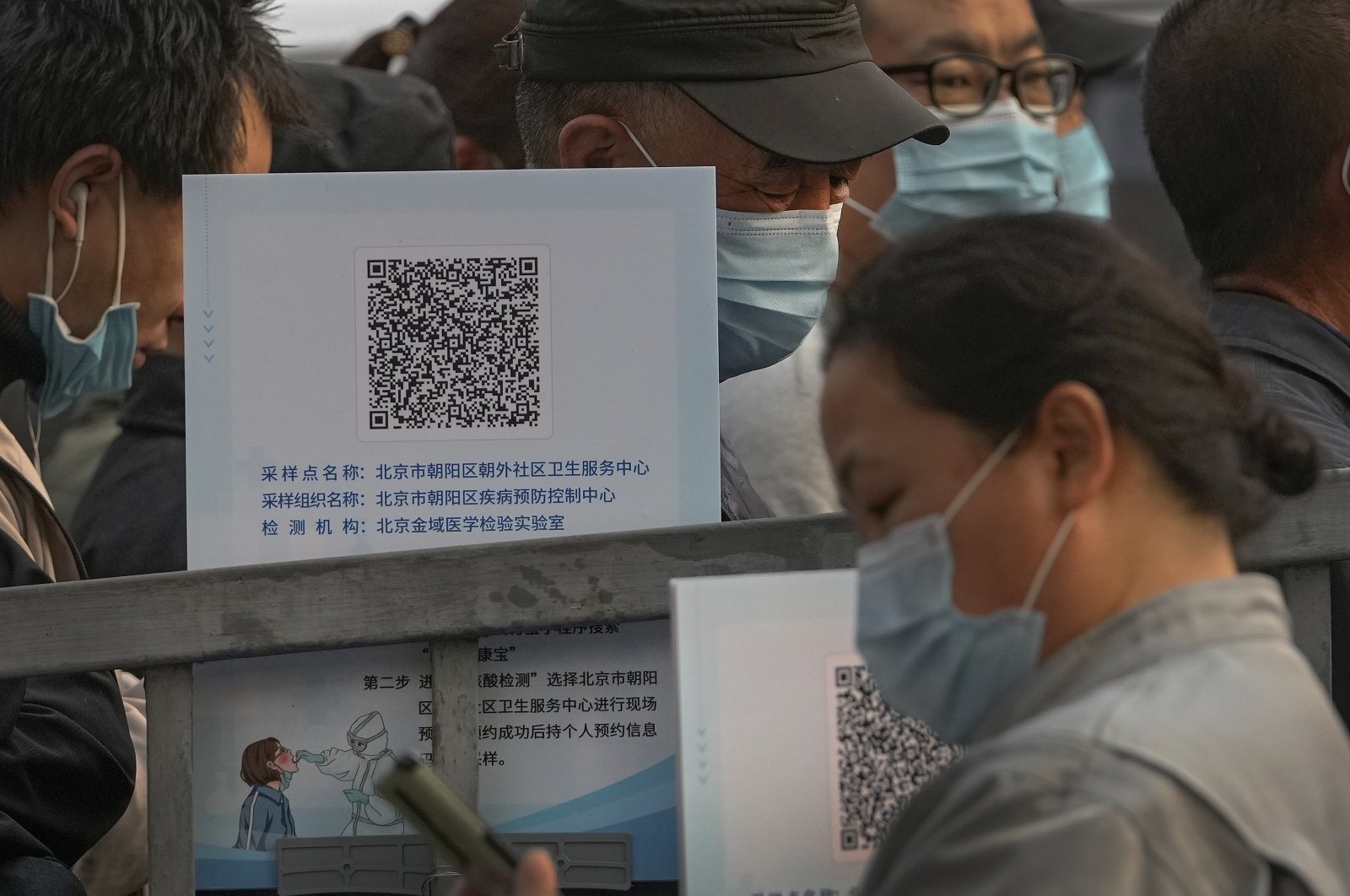 Service sector workers wearing face masks to help curb the spread of the coronavirus line up to receive a swab for the COVID-19 test during mass testing in Beijing, China, Oct. 29, 2021. (AP Photo)