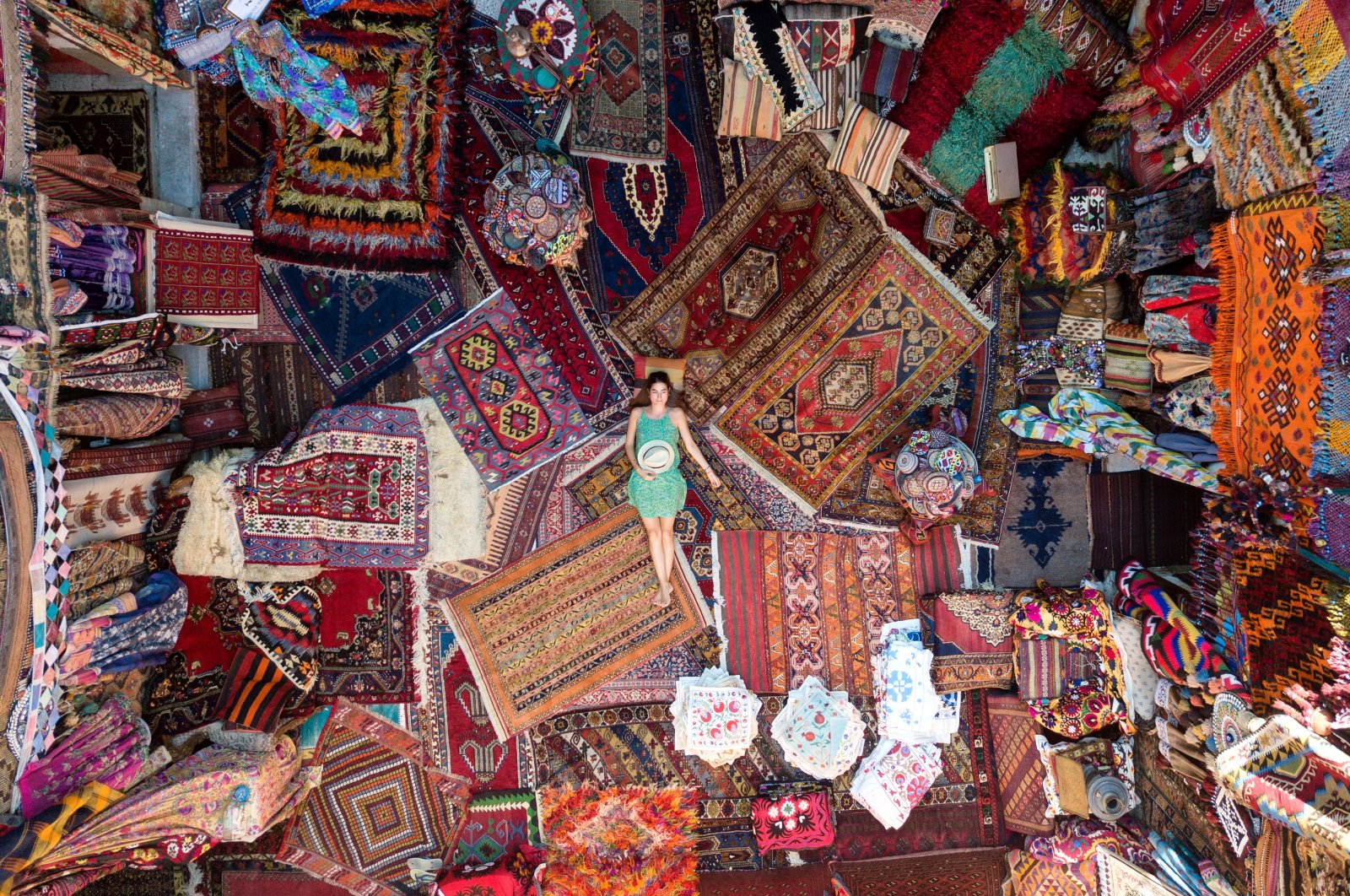 A tourist poses on hand-woven carpets in a historical inn converted into a carpet shop in Göreme, Nevşehir, central Turkey. (Getty Images) 