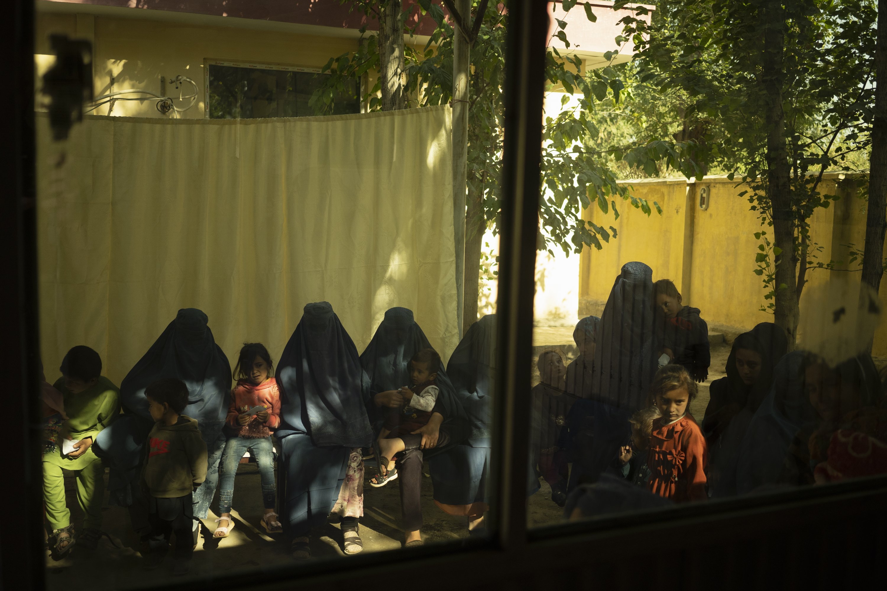 Patients are seen waiting through the window of a doctor