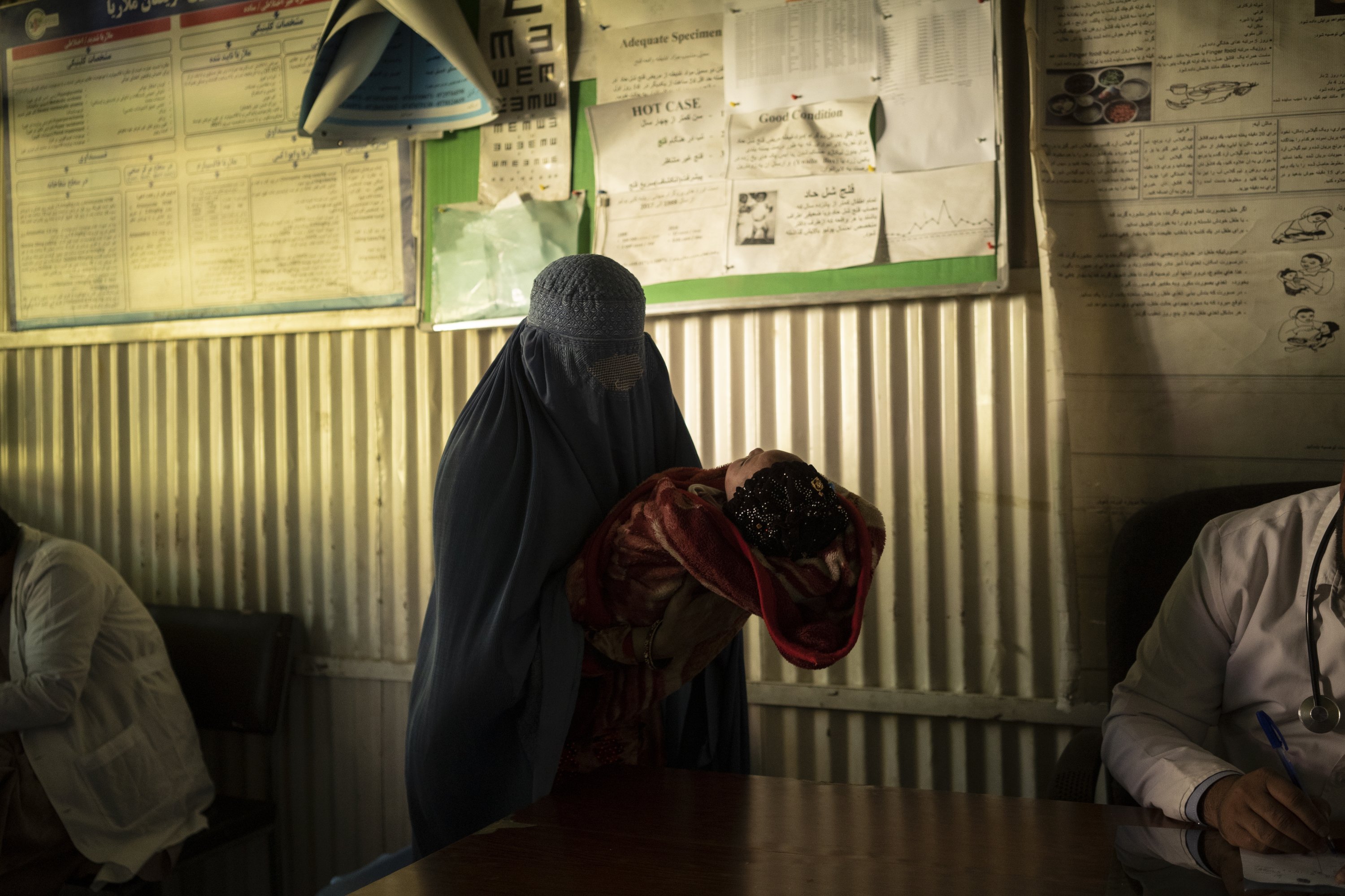 A woman holds her baby before seeing the doctor in the hospital in Mirbacha Kot, Afghanistan, Oct. 25, 2021. (AP Photo)