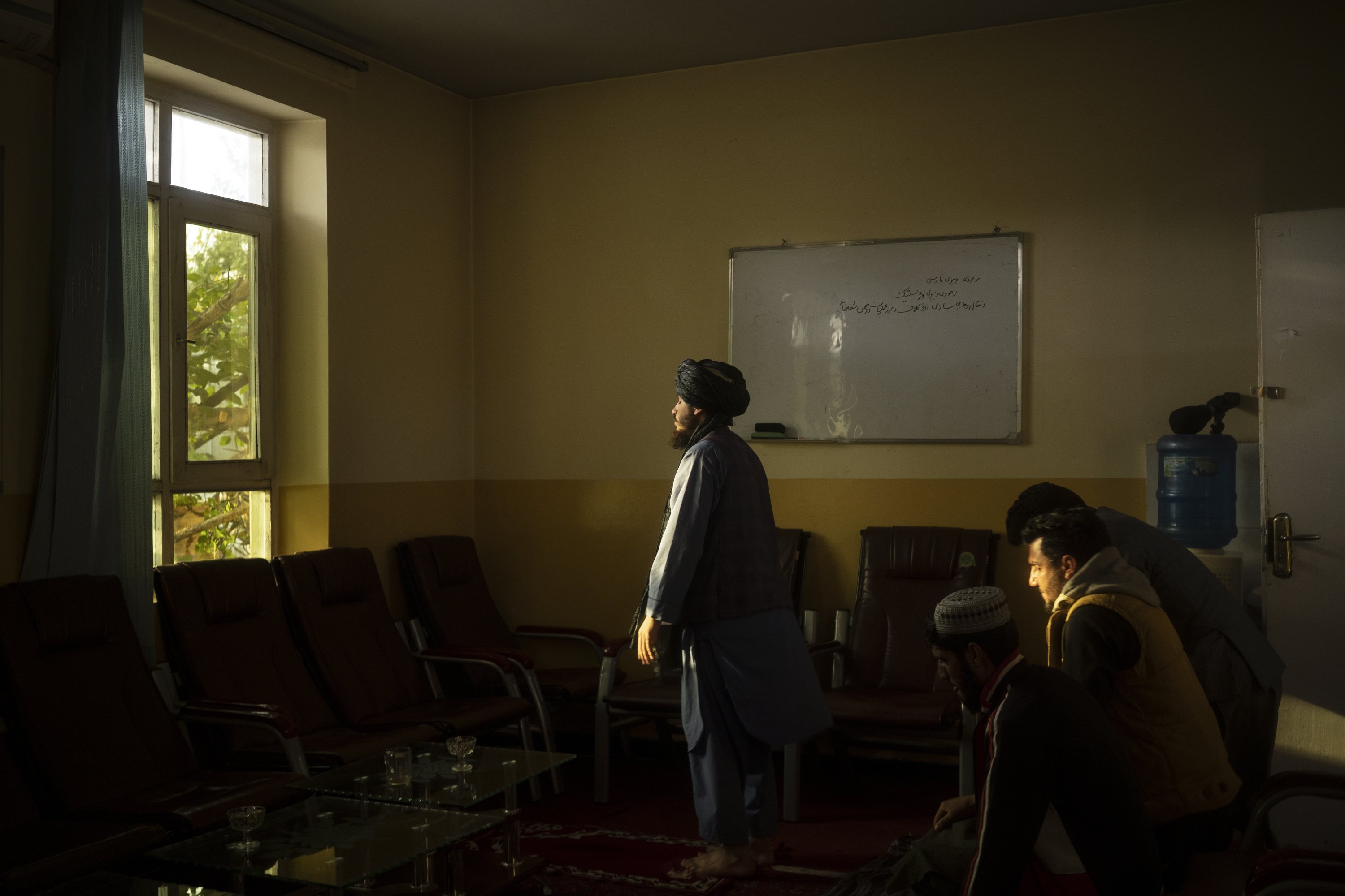 Taliban member Mohammad Javid Ahmadi, 22, prays with colleagues inside an office in the hospital in Mirbacha Kot, Afghanistan, Oct. 26, 2021. (AP Photo)