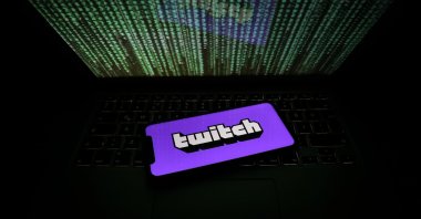 An iPhone with Twitch logo is seen next to a laptop displaying the Matrix digital rain is seen in this file photo taken on June 10, 2021 (AA Photo)