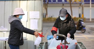 A volunteer spraying disinfectant on bags containing food that will be distributed to residents at a restricted residential area due to the spread of COVID-19 in Zhangye, northwestern Gansu province, in China, Oct. 31, 2021. (AFP Photo)
