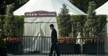 A worker wearing a face mask to help protect from the coronavirus walks by a closed temperature screening booth set up at the entrance gate to the Shanghai Disney Resort in Shanghai, China, Nov. 1, 2021. (AP Photo)
