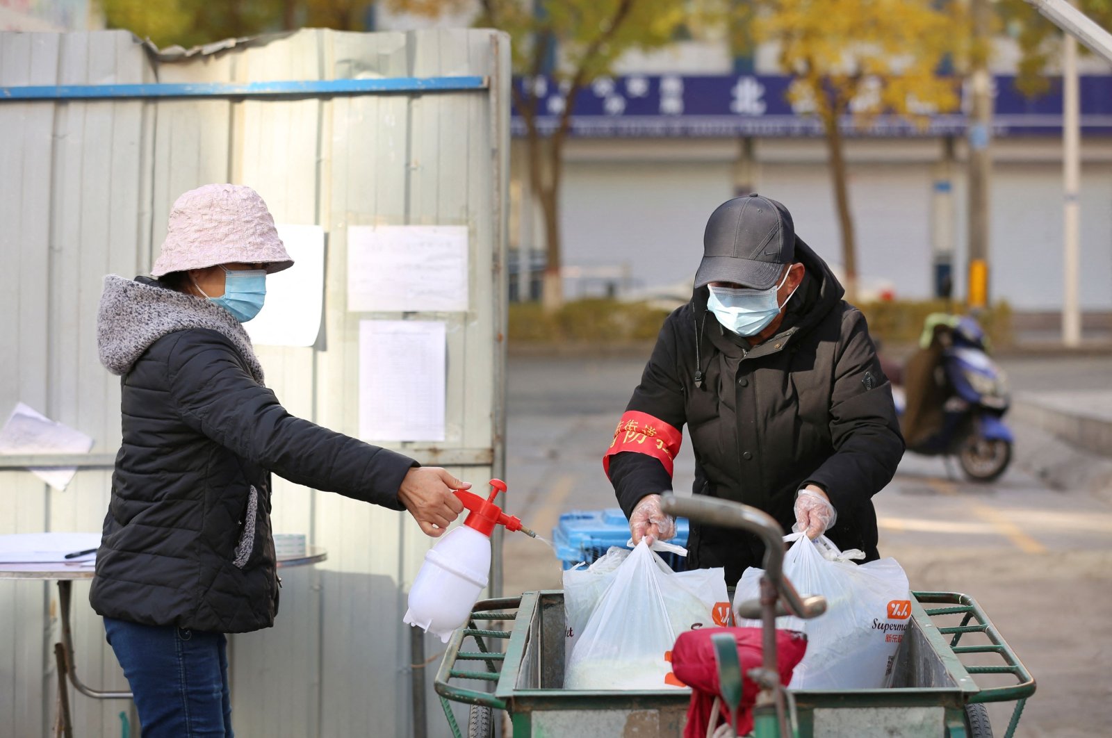 A volunteer spraying disinfectant on bags containing food that will be distributed to residents at a restricted residential area due to the spread of COVID-19 in Zhangye, northwestern Gansu province, in China, Oct. 31, 2021. (AFP Photo)