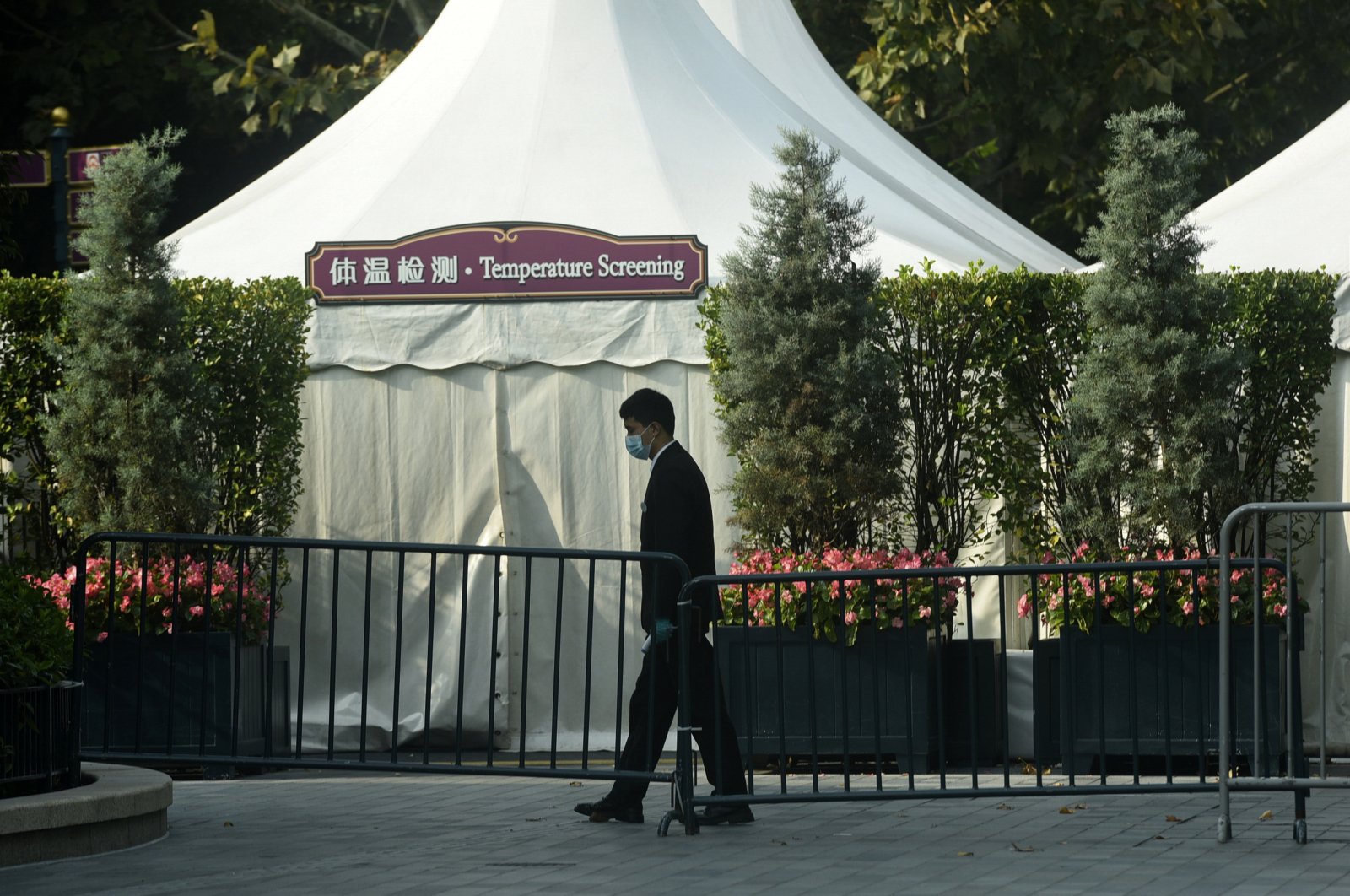 A worker wearing a face mask to help protect from the coronavirus walks by a closed temperature screening booth set up at the entrance gate to the Shanghai Disney Resort in Shanghai, China, Nov. 1, 2021. (AP Photo)