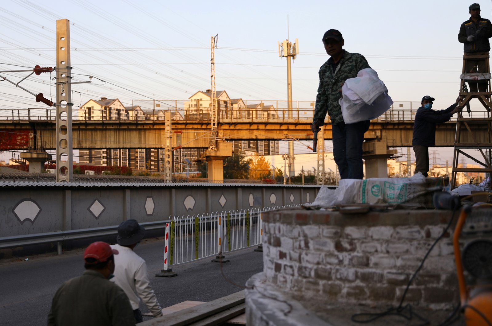 Construction workers work near residential buildings and railway tracks in Beijing, China, Oct. 31, 2021. (Reuters Photo)