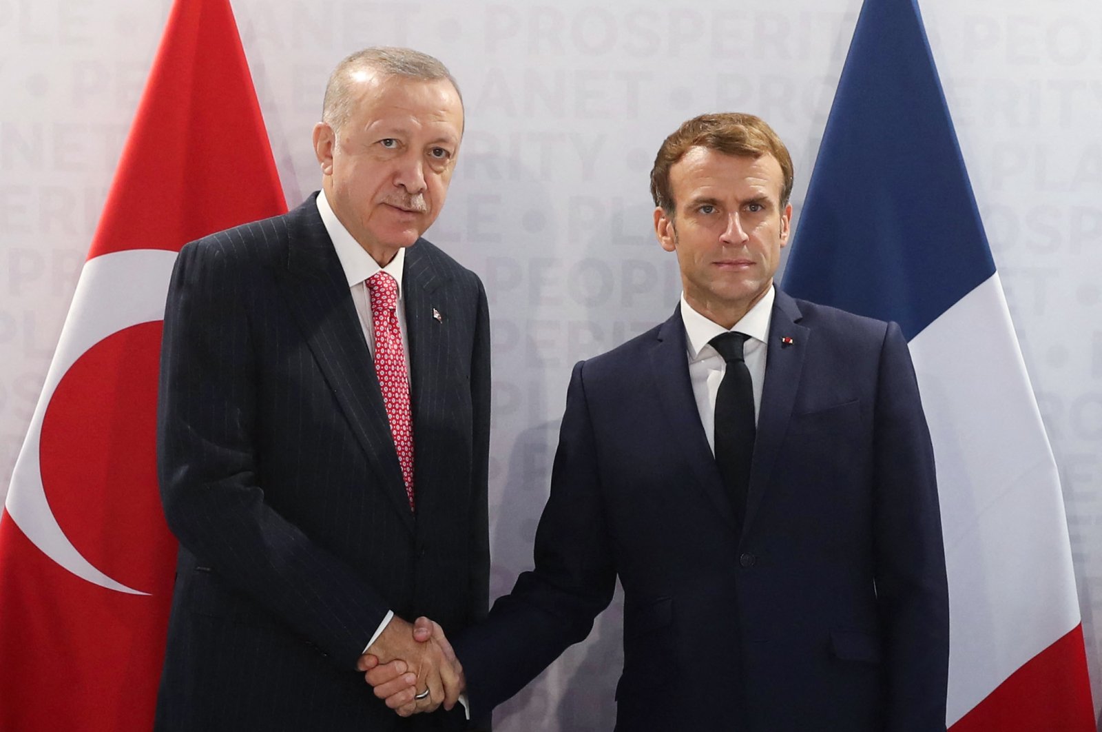 This handout photograph by the Turkish Presidential Press Service shows President Recep Tayyip Erdoğan (L) and French President Emmanuel Macron (R) shaking hands before their bilateral meeting during the G-20 Summit at the Roma Convention Center La Nuvola, in Rome, Italy, Oct. 31, 2021, (AFP Photo)